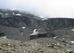 Il Rifugio Chiarella-Amiante, sullo sfondo a destra la bastionata rocciosa da superare per avvicinarsi alla cima